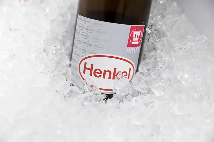 Garrafa âmbar de vidro com o rótulo da Henkel, mergulhada em gelo