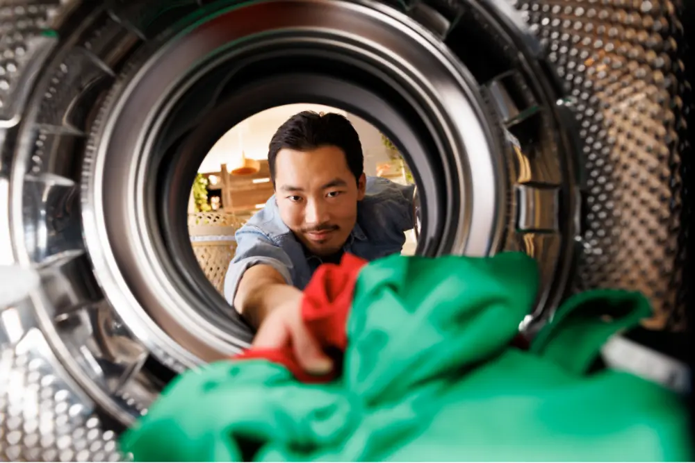 Imagem de um homem colocando roupas em uma máquina industrial