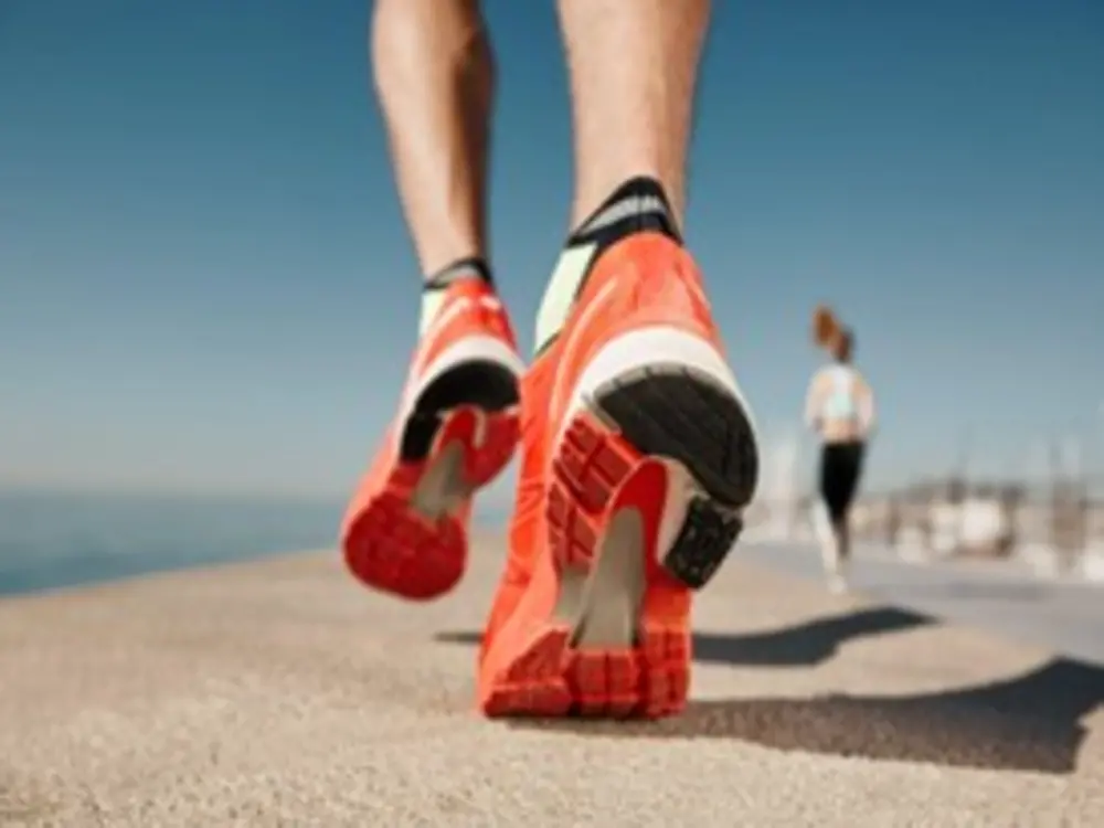Imagem de uma pessoa correndo com um tênis laranja