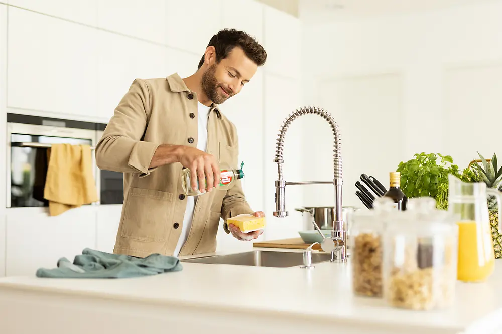 Homem na cozinha lavando louça