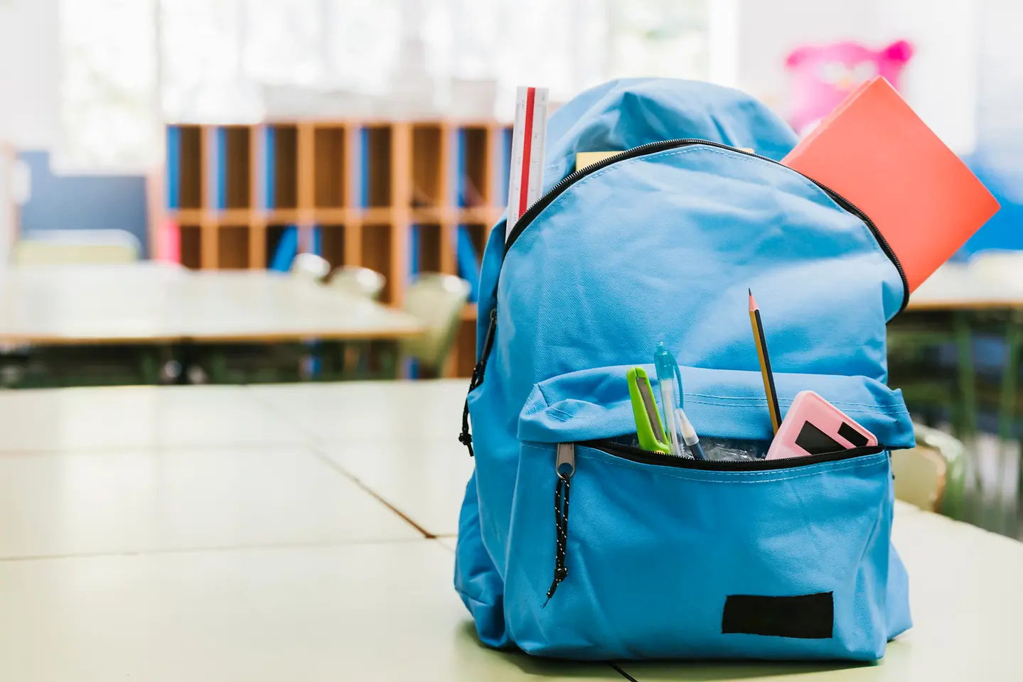 Imagem de uma mochila azul com materiais escolares