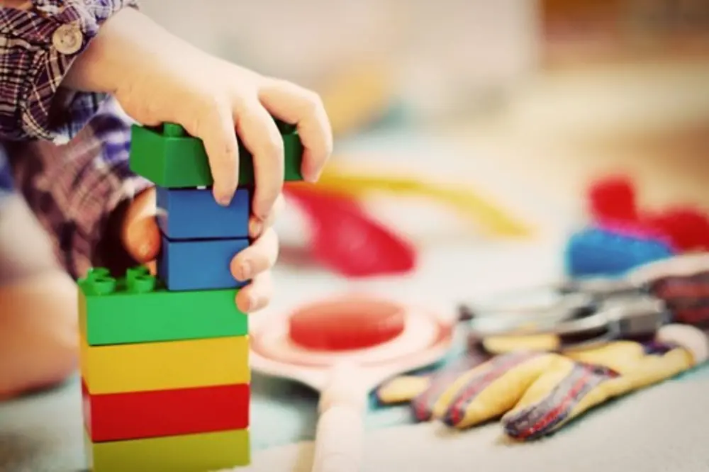 Imagem de uma criança com brinquedos coloridos nas mãos