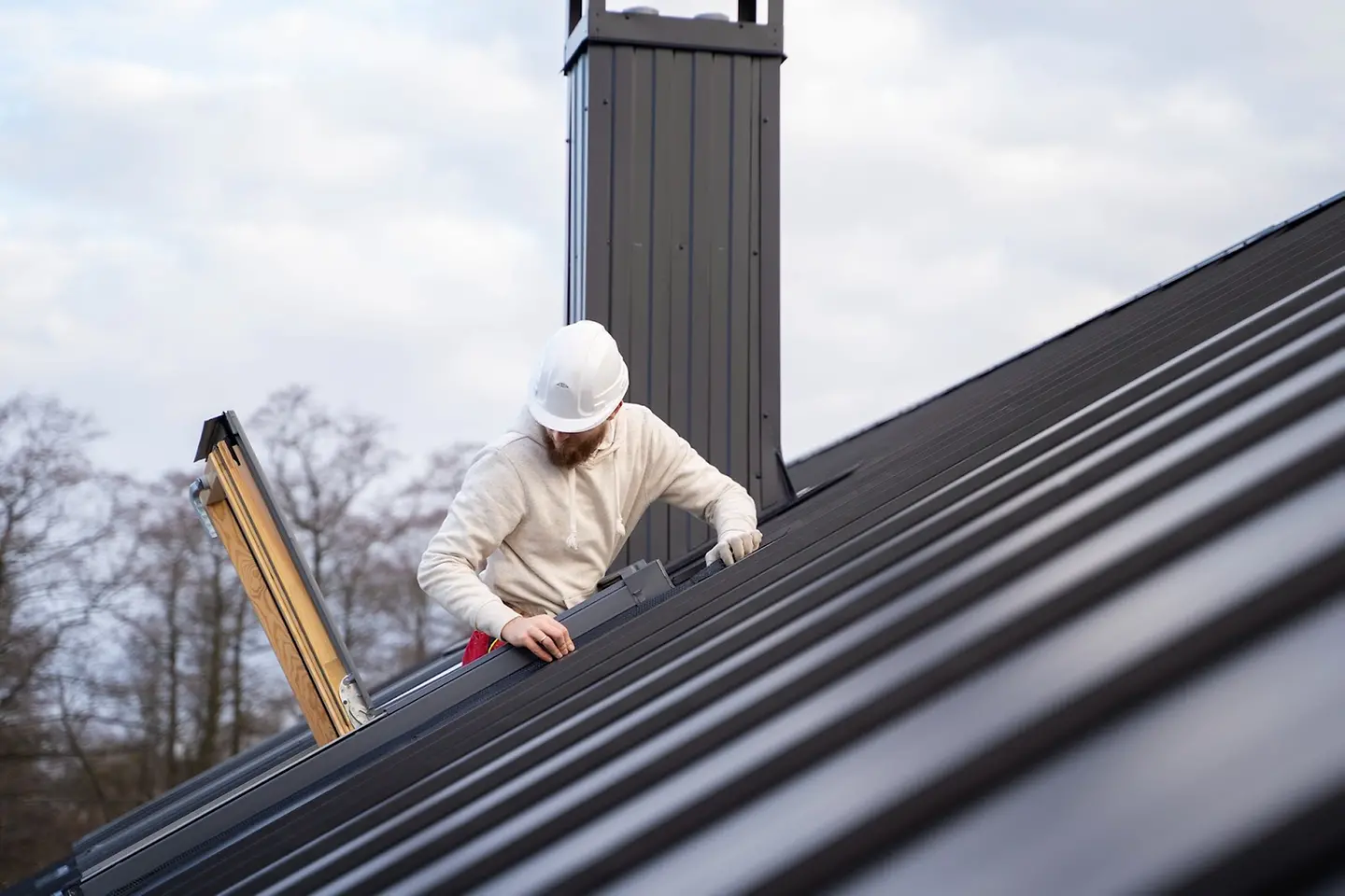 profissional em cima do telhado mexendo na calha de uma casa