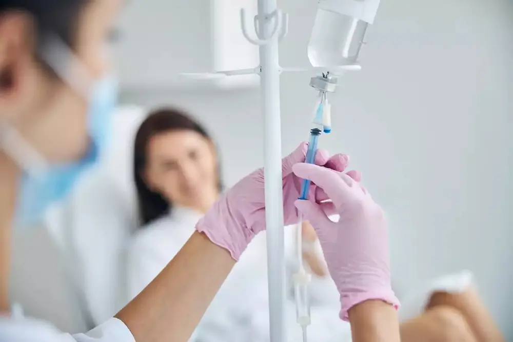 Profissional de saúde segurando uma bolsa de soro intravenoso em um ambiente hospitalar.