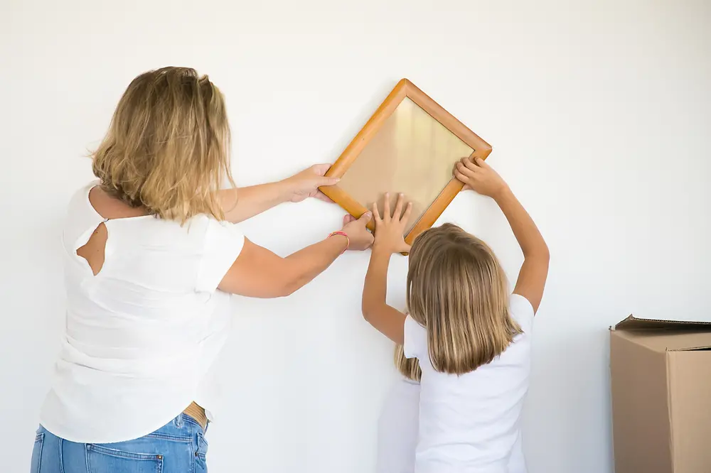 Mãe e filha realizando uma colagem na parede