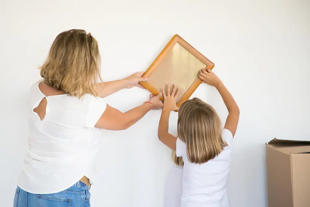 Mãe e filha realizando uma colagem na parede