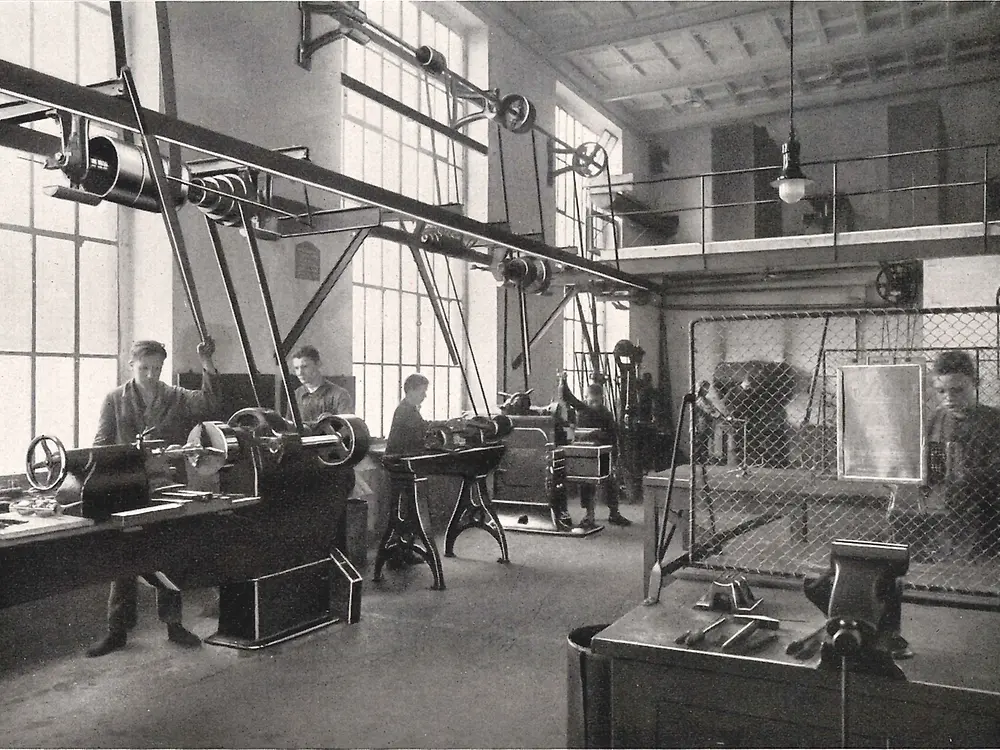 Aprendizes trabalhando em máquinas na oficina de metalurgia.