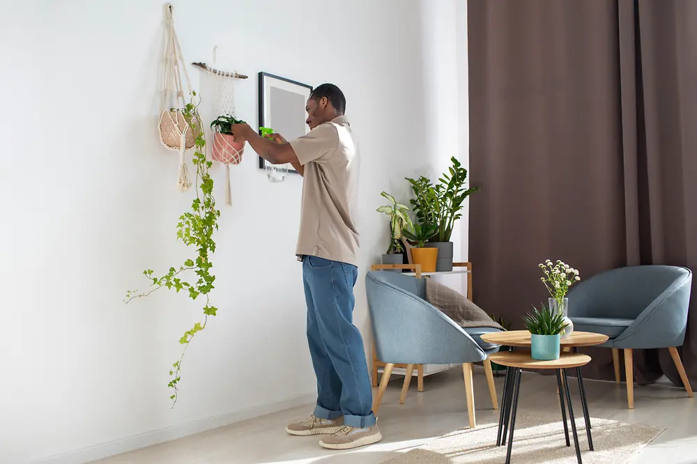 Decorador em pé ajusta itens na sala durante a montagem do ambiente.