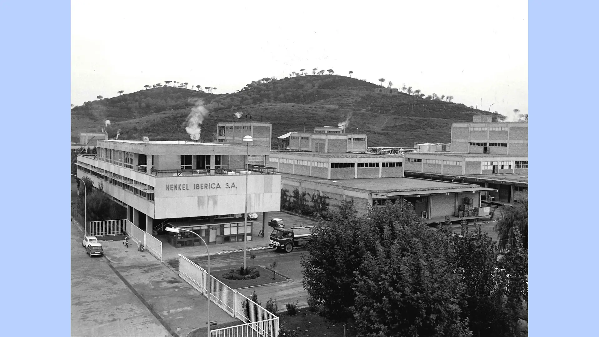 Imagem em preto e branco do exterior do site de Montornès. A foto mostra o complexo industrial com seus diversos edifícios cercados pelas colinas e montanhas da região.
