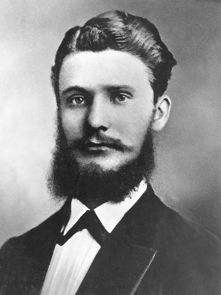Retrato histórico em preto e branco de Fritz Henkel em traje formal, com barba cheia e cabelo bem penteado.