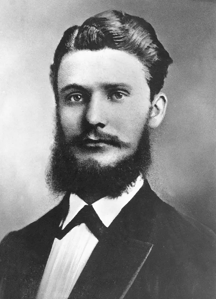 Retrato histórico em preto e branco de Fritz Henkel em traje formal, com barba cheia e cabelo bem penteado.